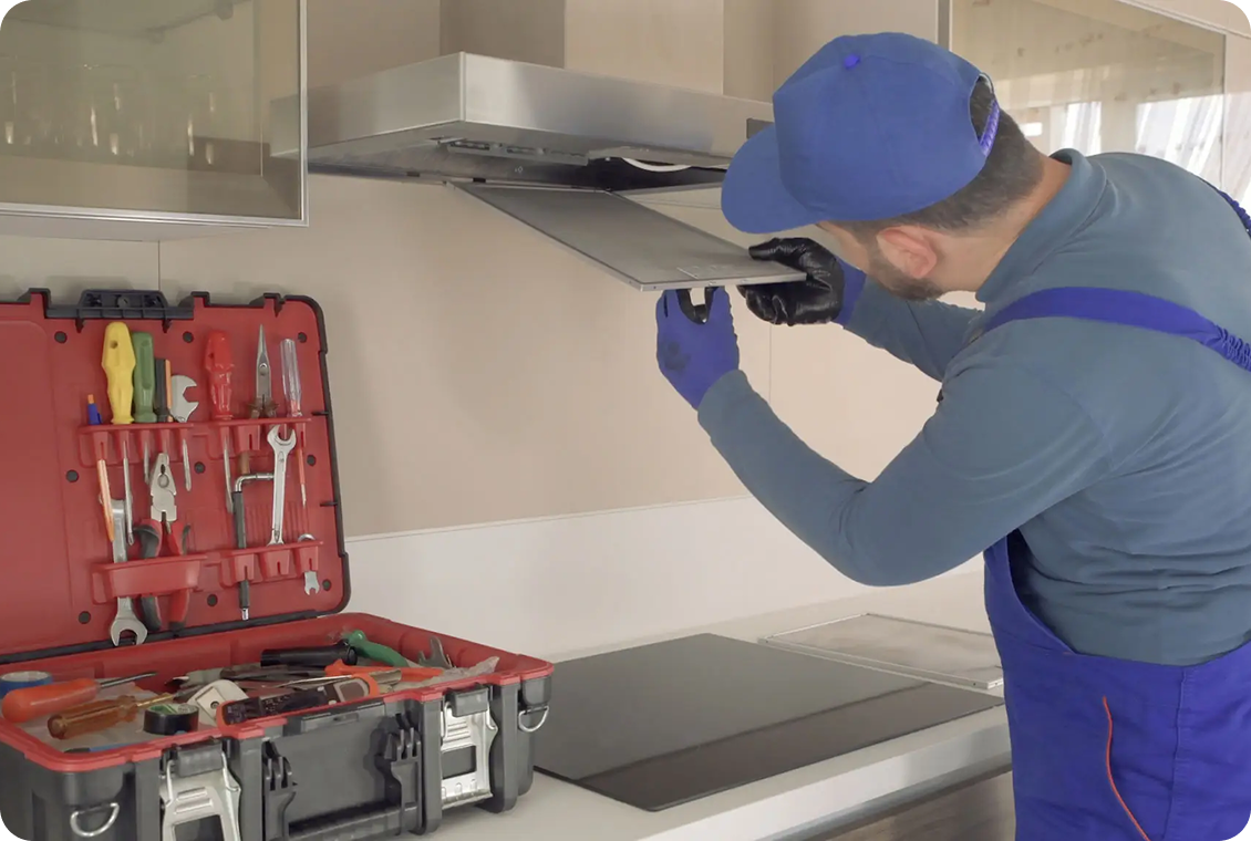 Technician repairing kitchen range hood.